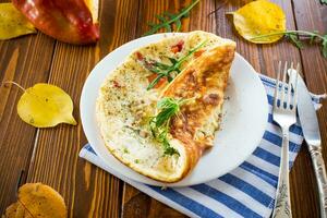 Fried omelettes with various autumn vegetables in a plate on a wooden table. photo