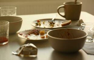 Empty dirty plates with spoons and forks on the table after meal. Banquet ending concept. Unwashed dishes photo