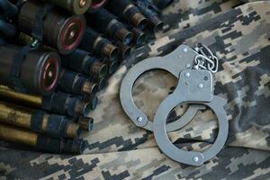 Ukrainian army machine gun belt shells and handcuffs on military uniform. Concept of bribery and war crimes photo