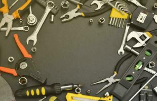 Handyman tool kit on black wooden table with copy space. Many wrenches and screwdrivers, pilers and other tools for any types of repair or construction works. Repairman tools photo