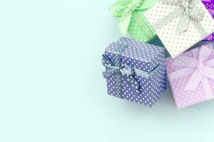 Pile of a small colored gift boxes with ribbons lies on a violet background. Minimalism flat lay top view photo