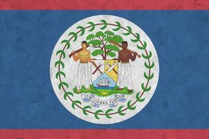 Belize flag depicted in bright paint colors on old relief plastering wall. Textured banner on rough background photo