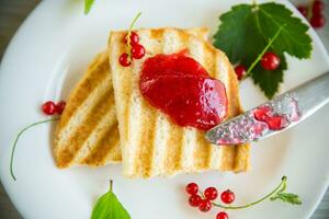 fried bread croutons for breakfast with redcurrant jam in a plate with berries photo