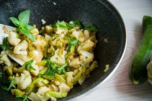 cauliflower fried with zucchini and vegetables in a pan photo