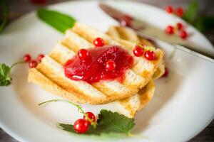fried bread croutons for breakfast with redcurrant jam in a plate with berries photo