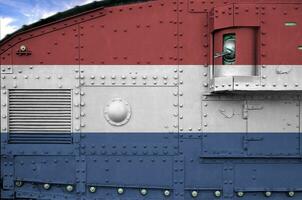 Netherlands flag depicted on side part of military armored tank closeup. Army forces conceptual background photo