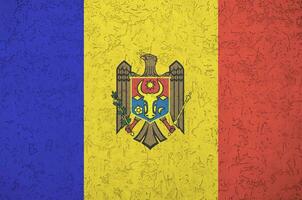 Moldova flag depicted in bright paint colors on old relief plastering wall. Textured banner on rough background photo