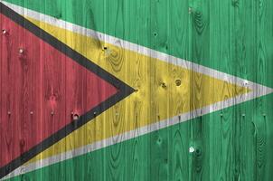 Guyana flag depicted in bright paint colors on old wooden wall. Textured banner on rough background photo