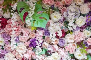 Floral background. Lot of artificial flowers in colorful composition on handmade wooden pink background photo