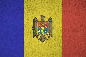 Moldova flag depicted in bright paint colors on old relief plastering wall. Textured banner on rough background photo