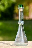 a glass flask with a green lid sitting on a wooden table photo