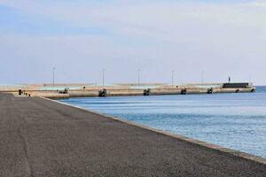 un largo la carretera líder a un muelle con un azul cielo foto