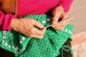 an old woman is knitting a green crocheted bag photo