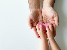 child gives adult small red paper heart. Fathers Day. Family, love, parents photo