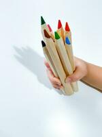 Childs hand holds colored pencils. Learning and drawing concept photo