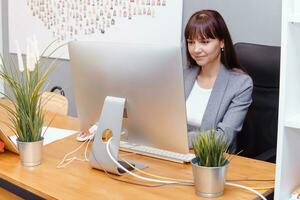 A brunette woman at a computer in the workplace. Business concept. photo