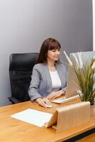 A brunette woman at a computer in the workplace. Business concept. photo