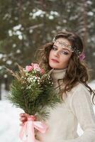 Beautiful bride in a white dress with a bouquet in a snow-covered winter forest. Portrait of the bride in nature photo