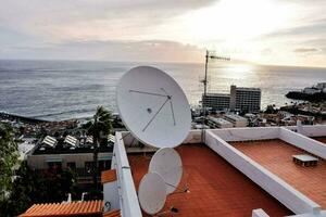 a satellite dish on top of a roof overlooking the ocean photo