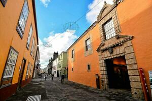 a narrow street with orange buildings and a blue sky photo