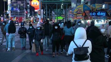 nuovo York città, Stati Uniti d'America - gennaio 23, 2021 persone indossare maschere attraversamento un' strada a volte piazza a notte durante coronavirus pandemia nel inverno giorno. macchine passaggio di. midtown Manhattan video