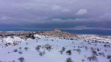 Landscape of Cappadocia and Uchisar Castle Carved in Stone in Winter. Snowy Hills. Turkey. Aerial View. Stormy Sky. Drone Flies Forward and Upwards video