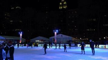 Neu York Stadt, USA - - Januar 23, 2021 Menschen tragen Masken Schlittschuhlaufen auf Eisbahn beim Bryant Park im Manhattan im Winter Abend während covid-19 Pandemie. video