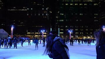 nuovo York città, Stati Uniti d'America - gennaio 23, 2021 persone indossare maschere Pattinaggio sul ghiaccio su pista di pattinaggio a bryant parco nel Manhattan nel inverno sera. video
