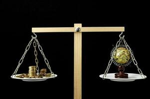 a balance scale with coins and a globe photo
