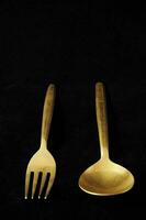 a gold fork and spoon on a black surface photo