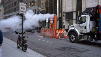 nuovo York città, Stati Uniti d'America - gennaio 23, 2021 vapore vapore essere ventilato attraverso un arancia e bianca pila nel Manhattan. strada e camion. macchine e persone passaggio di video