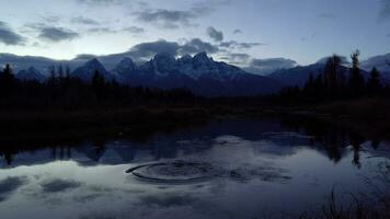 teton montaña rango y reflexión en serpiente río a noche crepúsculo. schwabacher aterrizaje. grandioso teton nacional parque, Wyoming, EE.UU. amplio disparo. lanzamiento roca, comenzando olas video