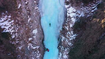Mann ist führen auf Eis. Eis Klettern auf gefroren Wasserfall, Antenne Sicht. Barskoon Schlucht, Kirgistan. Drohne fliegt nach vorne, Neigung Nieder video