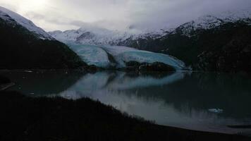 portage glaciär, portage sjö, reflexion och snötäckt bergen på solig dag. alaska, usa. antenn se. Drönare flugor bakåt och uppåt video