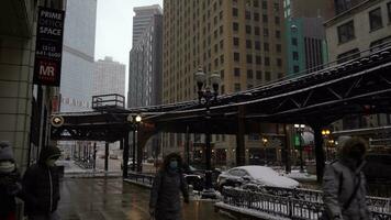 chicago, Estados Unidos - enero 25, 2021 elevado chicago l tren en chicago lazo en un nublado día. nevando personas vistiendo mascaras durante coronavirus pandemia video