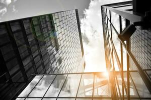 Modern architectural details. Modern glass facade with a geometric pattern. Contemporary corporate business architecture. Red sun on horizon. Black and white toned image. photo