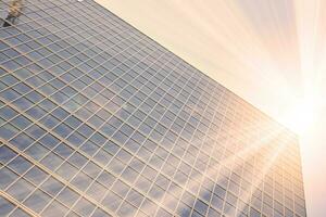 Glass building with transparent facade of the building and blue sky. Structural glass wall reflecting blue sky. Abstract modern architecture fragment. Contemporary architectural background. photo