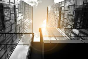 Modern architectural details. Modern glass facade with a geometric pattern. Contemporary corporate business architecture. Red sun on horizon. Black and white toned image. photo