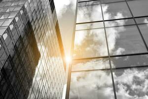 Modern architectural details. Modern glass facade with a geometric pattern. Contemporary corporate business architecture. Red sun on horizon. Black and white toned image. photo