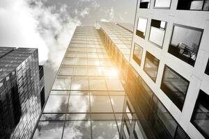 Modern architectural details. Modern glass facade with a geometric pattern. Contemporary corporate business architecture. Red sun on horizon. Black and white toned image. photo