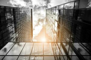 Modern architectural details. Modern glass facade with a geometric pattern. Contemporary corporate business architecture. Red sun on horizon. Black and white toned image. photo