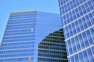 Glass building with transparent facade of the building and blue sky. Structural glass wall reflecting blue sky. Abstract modern architecture fragment. Contemporary architectural background. photo