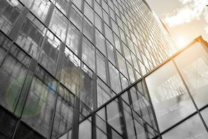 Modern architectural details. Modern glass facade with a geometric pattern. Contemporary corporate business architecture. Red sun on horizon. Black and white toned image. photo