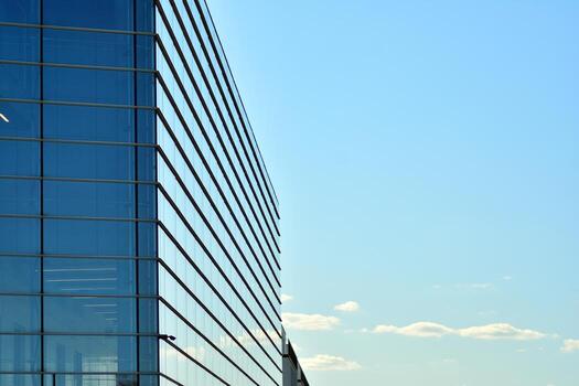 Glass building with transparent facade of the building and blue sky. Structural glass wall reflecting blue sky. Abstract modern architecture fragment. Contemporary architectural background. photo