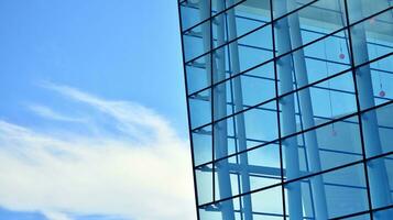 Glass building with transparent facade of the building and blue sky. Structural glass wall reflecting blue sky. Abstract modern architecture fragment. Contemporary architectural background. photo