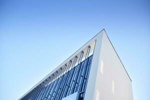 Glass building with transparent facade of the building and blue sky. Structural glass wall reflecting blue sky. Abstract modern architecture fragment. Contemporary architectural background. photo