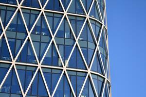 Glass building with transparent facade of the building and blue sky. Structural glass wall reflecting blue sky. Abstract modern architecture fragment. Contemporary architectural background. photo