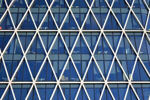 Glass building with transparent facade of the building and blue sky. Structural glass wall reflecting blue sky. Abstract modern architecture fragment. Contemporary architectural background. photo