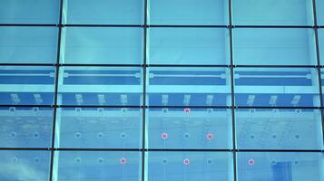 Glass building with transparent facade of the building and blue sky. Structural glass wall reflecting blue sky. Abstract modern architecture fragment. Contemporary architectural background. photo