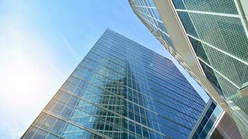 Glass building with transparent facade of the building and blue sky. Structural glass wall reflecting blue sky. Abstract modern architecture fragment. Contemporary architectural background. photo